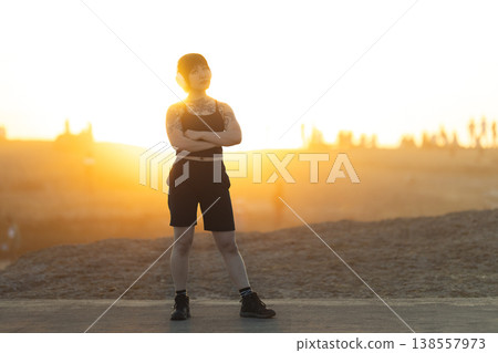 Confident young woman with tattoos standing at sunset Confident young woman with tattoos standing at sunset 138557973
