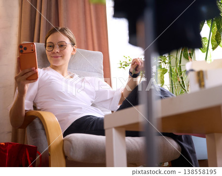 Woman relaxing in armchair using smartphone after online shopping Woman relaxing in armchair using smartphone after online shopping 138558195