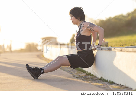 Woman doing tricep dips in outdoor workout Woman doing tricep dips in outdoor workout 138558311