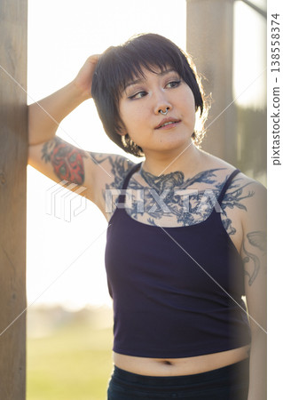 Young woman with tattoos posing outdoors looking away Young woman with tattoos posing outdoors looking away 138558374