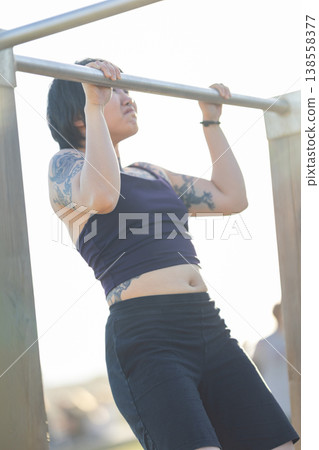 Woman building strength exercising doing outdoor pull-ups Woman building strength exercising doing outdoor pull-ups 138558377