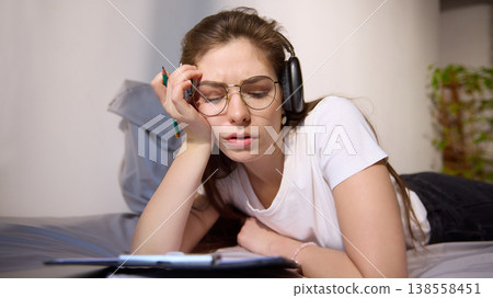 Young woman feeling tired while studying online with headphones at home. Young woman feeling tired while studying online with headphones at home. 138558451