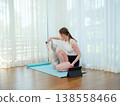 Young woman resting after workout at home with her cat. Concept of fitness, pet companionship, and healthy lifestyle. Female relaxing on yoga mat and playing with domestic animal. 138558466
