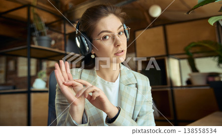 Woman with headphones showing three steps during online coaching session. Woman with headphones showing three steps during online coaching session. 138558534