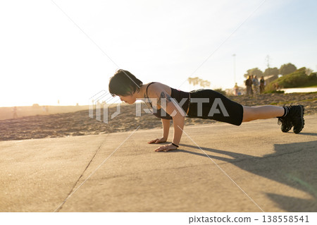 Woman exercising outdoors doing push-up on pathway Woman exercising outdoors doing push-up on pathway 138558541