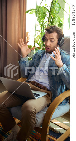 Surprised man with headphones reacting during online coaching video call. 138558547