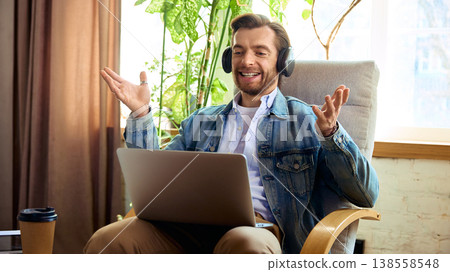 Happy man with headphones celebrating success during online coaching session. 138558548