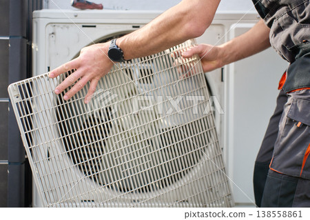 Technician removing cover from outdoor heat pump unit Technician removing cover from outdoor heat pump unit 138558861