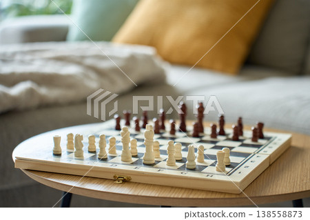 Wooden chess board with pieces on table in living room Wooden chess board with pieces on table in living room 138558873