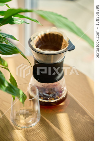 Fresh brewed coffee in filter dripper with glass on table Fresh brewed coffee in filter dripper with glass on table 138558899