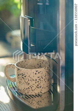 Ceramic cup under coffee machine spout in kitchen close up 138558907