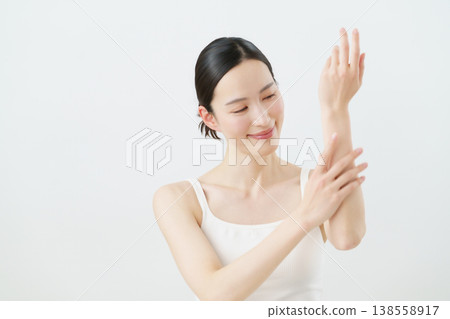A young Japanese woman giving a hand massage against a white background. A young Japanese woman giving a hand massage against a white background. 138558917