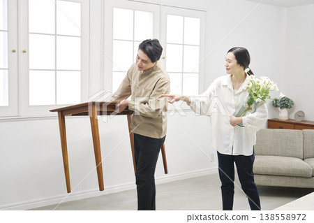 A couple carrying a table during a room makeover. A couple carrying a table during a room makeover. 138558972