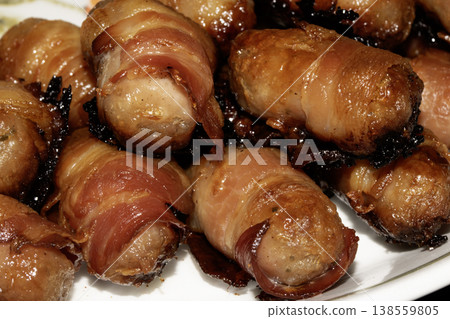 Close up of chipolatas pigs in blankets sausages wrapped in bacon on white background Close up of chipolatas pigs in blankets sausages wrapped in bacon on white background 138559805
