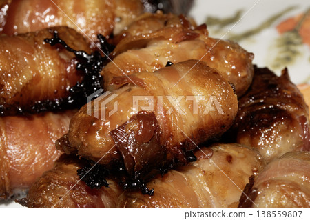 Close up of chipolatas pigs in blankets sausages wrapped in bacon on white background Close up of chipolatas pigs in blankets sausages wrapped in bacon on white background 138559807