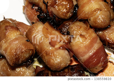 Close up of chipolatas pigs in blankets sausages wrapped in bacon on white background Close up of chipolatas pigs in blankets sausages wrapped in bacon on white background 138559810