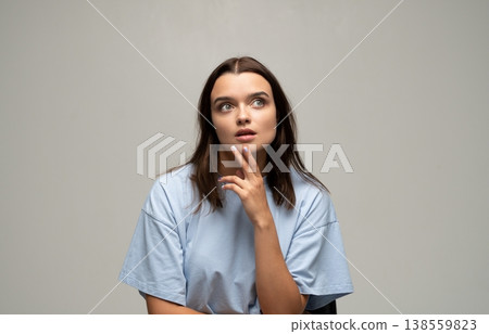 Young woman with pensive expression looking up, deep in thought, brainstorming and having a thoughtful moment 138559823