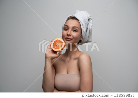 Young woman with natural fresh skin and towel on head holding a grapefruit half, symbolizing healthy beauty, wellness, and organic skincare on a clean background Young woman with natural fresh skin and towel on head holding a grapefruit half, symbolizing healthy beauty, wellness, and organic skincare on a clean background 138559855