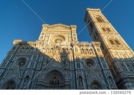A low-angle view of the Florence Cathedral's facade and Giotto's Campanile under a clear blue sky A low-angle view of the Florence Cathedral's facade and Giotto's Campanile under a clear blue sky 138560279