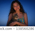 In the magic hour of twilight, a woman's gentle smile as she softly embraces her beloved cat, bathed in the blue veil of night. 138560286