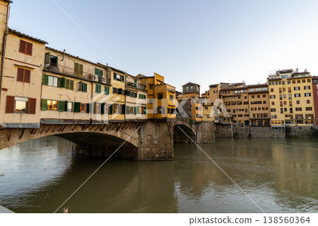 The historic Ponte Vecchio bridge spans the Arno River in Florence, Italy, lined with shops and buildings 138560364
