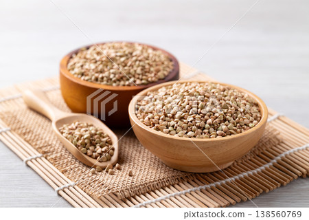 Raw organic buckwheat seeds in a wooden bowl and scoop, Food ingredient 138560769