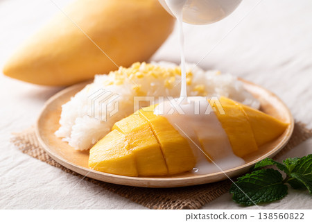 Pouring coconut milk sauce on Mango sticky rice (Khao Niew Mamuang) Pouring coconut milk sauce on Mango sticky rice (Khao Niew Mamuang) 138560822