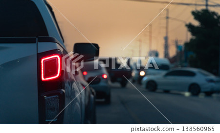 Abstract rear side of pickup car with turn on brake light. Driving on a congested rural road. Environment in the evening sky. With silhouette of electic pole and trees. Abstract rear side of pickup car with turn on brake light. Driving on a congested rural road. Environment in the evening sky. With silhouette of electic pole and trees. 138560965
