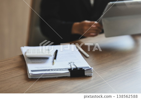 Close up image of a stack of papers and calculator on wooden office desk Close up image of a stack of papers and calculator on wooden office desk 138562588