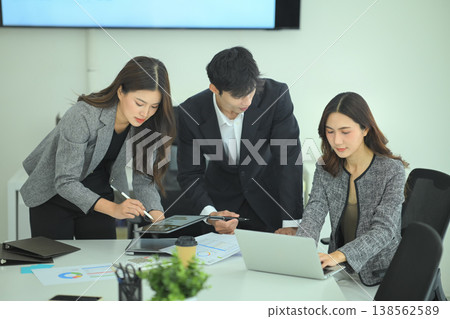 Professionals reviewing digital charts and printed reports during strategy meeting at desk Professionals reviewing digital charts and printed reports during strategy meeting at desk 138562589