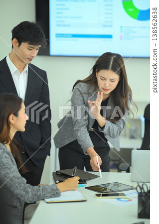 Three business professionals reviewing tablet data and reports during strategic meeting in modern office Three business professionals reviewing tablet data and reports during strategic meeting in modern office 138562638