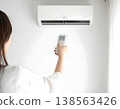 A beautiful woman turns on the air conditioner on a hot summer day. 138563426