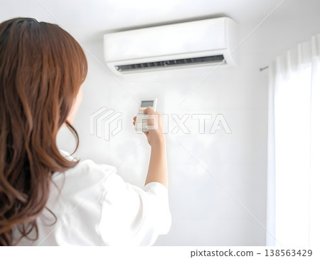 A young woman adjusts the temperature of the air conditioner. 138563429