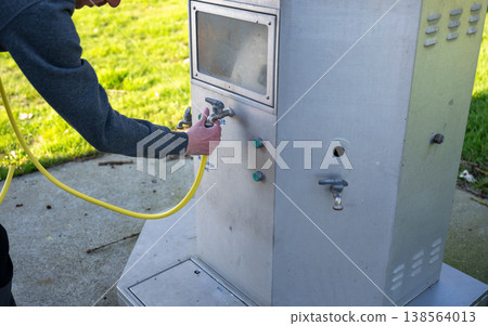 Connecting water hose to outdoor tap at campsite service station for camper van supply and travel utility concept 138564013