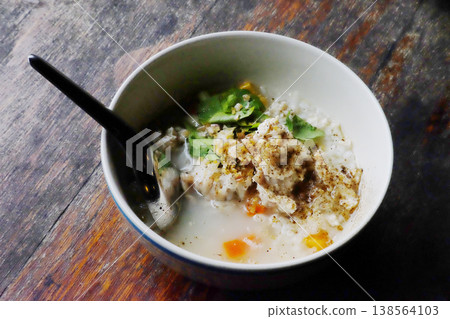 Top view of fresh Minced pork porridge in white bowl on wooden table is traditional breakfast Thai food 138564103