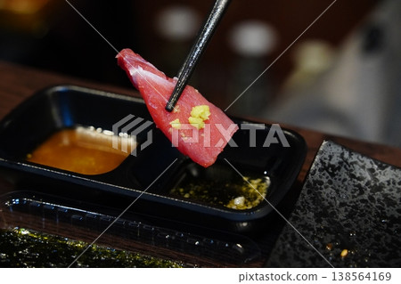 close-up photo of a piece of fresh tuna sashimi picked up with chopsticks. close-up photo of a piece of fresh tuna sashimi picked up with chopsticks. 138564169