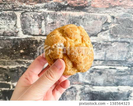 A fluffy cream puff held in my hand. A fluffy cream puff held in my hand. 138564323