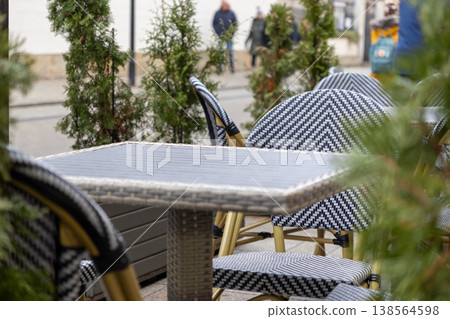 Empty outdoor cafe table and chairs featuring a decorative black and white chevron pattern, providing inviting seating on a quiet urban sidewalk Empty outdoor cafe table and chairs featuring a decorative black and white chevron pattern, providing inviting seating on a quiet urban sidewalk 138564598