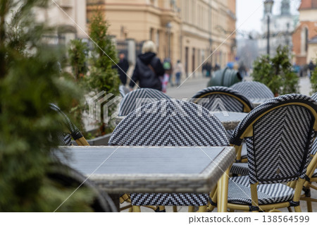 Empty outdoor cafe tables and chairs with a distinctive pattern await customers on a quiet city street, reflecting urban leisure and hospitality 138564599