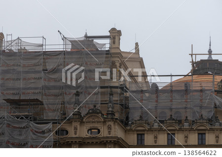 Ornate city building facade undergoes major renovation work, covered by extensive metal scaffolding and protective construction netting, highlighting urban restoration Ornate city building facade undergoes major renovation work, covered by extensive metal scaffolding and protective construction netting, highlighting urban restoration 138564622