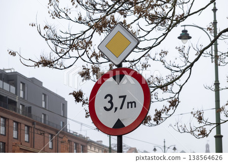 Urban street signs featuring a 3,7m height restriction and a prominent priority road symbol, ensuring safe traffic flow in the city Urban street signs featuring a 3,7m height restriction and a prominent priority road symbol, ensuring safe traffic flow in the city 138564626