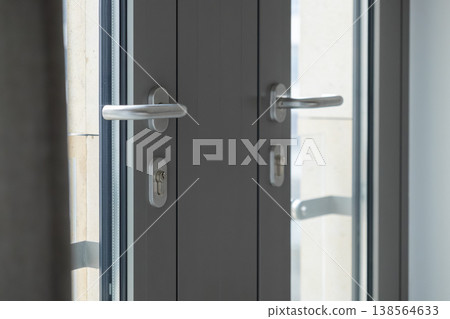 Modern gray double door with sleek silver handles and keyholes, emphasizing security and privacy for a contemporary home or office entrance 138564633