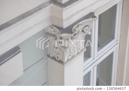Ornate architectural detail features a white column capital with acanthus leaves against a window pane, embodying classic design elements and historical architecture Ornate architectural detail features a white column capital with acanthus leaves against a window pane, embodying classic design elements and historical architecture 138564637