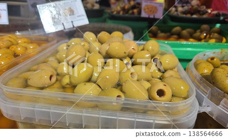 Closeup of green pitted olives in plastic container at market stall for food product background and ingredient packaging design Closeup of green pitted olives in plastic container at market stall for food product background and ingredient packaging design 138564666