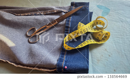 Denim jeans with scissors and yellow measuring tape for tailoring background and garment alteration design banner 138564669
