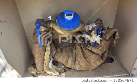 Residential water meter with insulated pipes inside a utility box for plumbing maintenance and supply system inspection 138564671