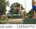 Young man doing a backflip into the river from a pier on a summer beach 138564753
