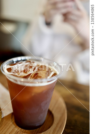 Close-up of iced coffee, cold drink, wooden coaster, cafe. Close-up of iced coffee, cold drink, wooden coaster, cafe. 138564865