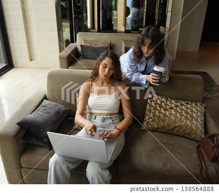 Two young women drink coffee in the co-working office Two young women drink coffee in the co-working office 138564888