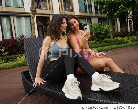 A woman captures her friend's relaxed pose while sitting on a lounge chair 138564889